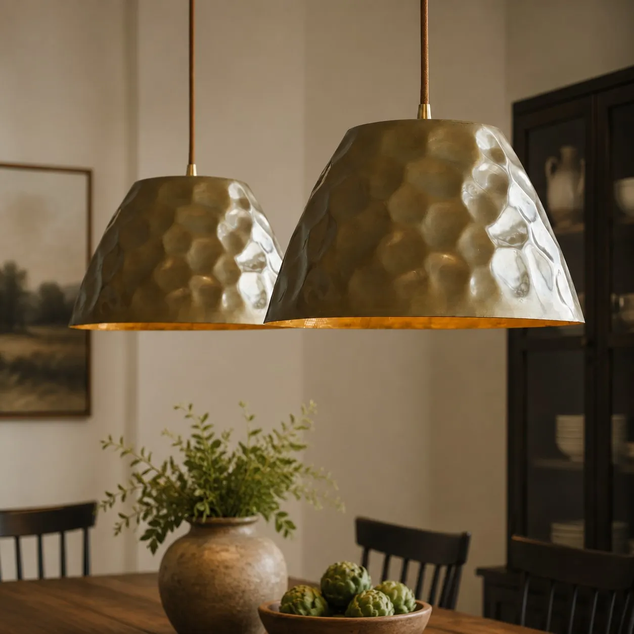 Pair of hammered brass pendant lights above a dining table